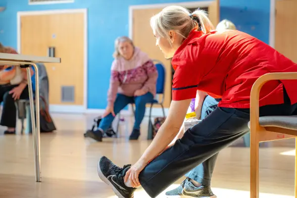 COPD Fitness Group_Weston FAHLC_SM Woman in red stretching her leg on a chair